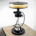 Vintage-style lamp with a metallic base and round shade on a wooden surface.