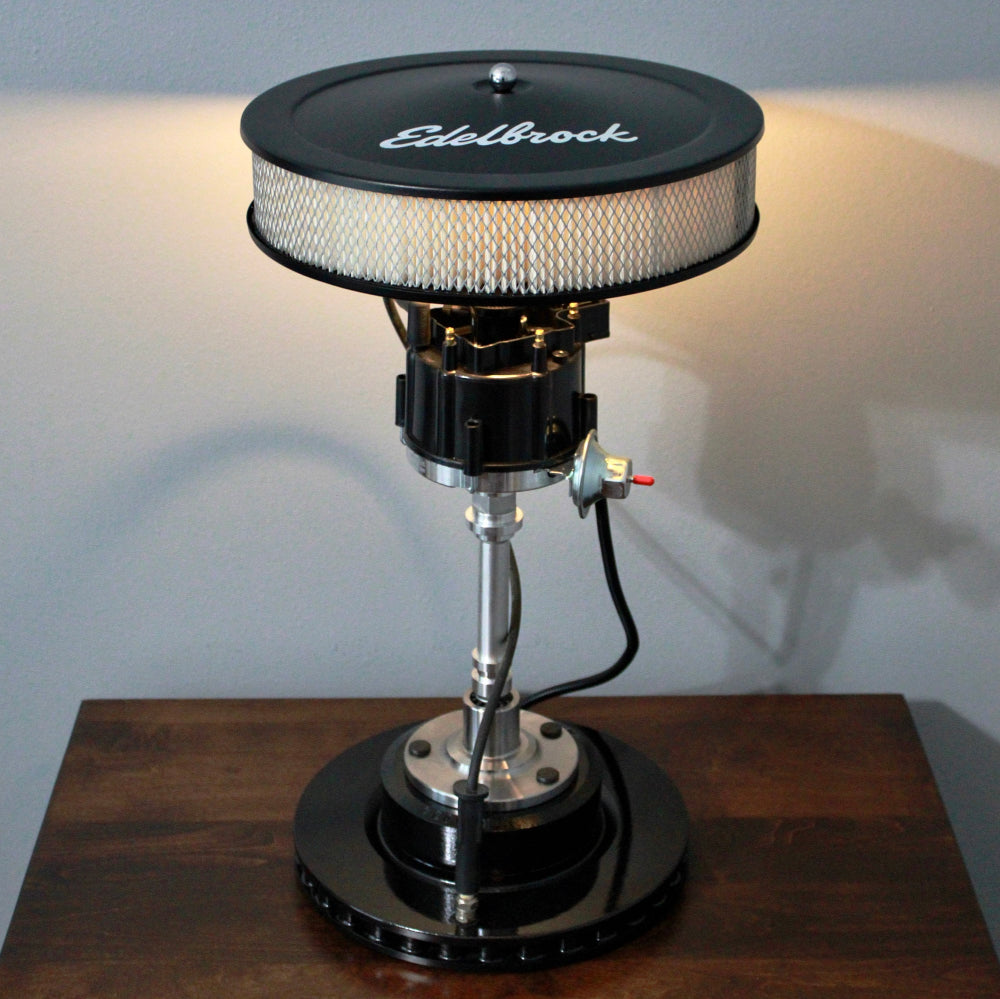 Vintage-style car engine lamp with 'Edelbrock' branding on a wooden base.