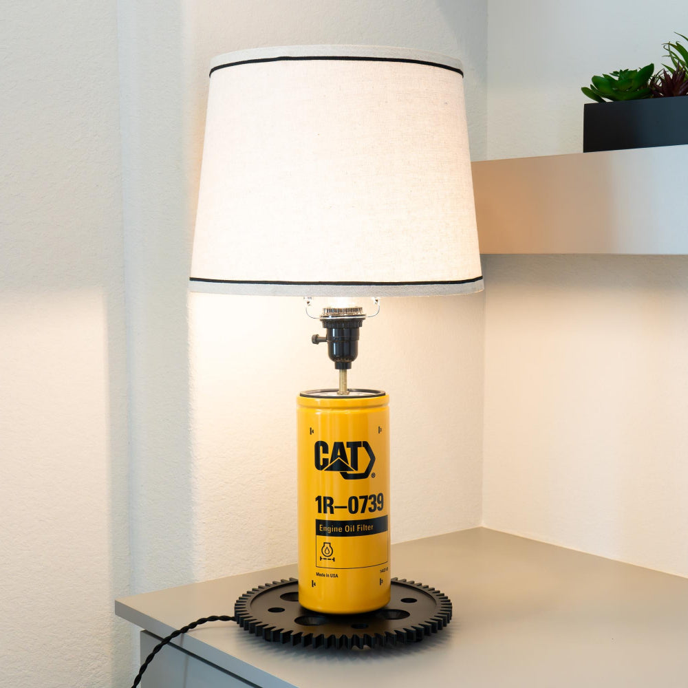 Lamp with a yellow cylindrical base featuring 'CAT' branding on a white surface.