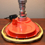 Red floor buffer on a wooden surface with a neutral background