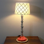 Table lamp with a patterned shade on a wooden surface against a plain wall