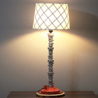 Decorative table lamp with a unique base and patterned shade on a plain background