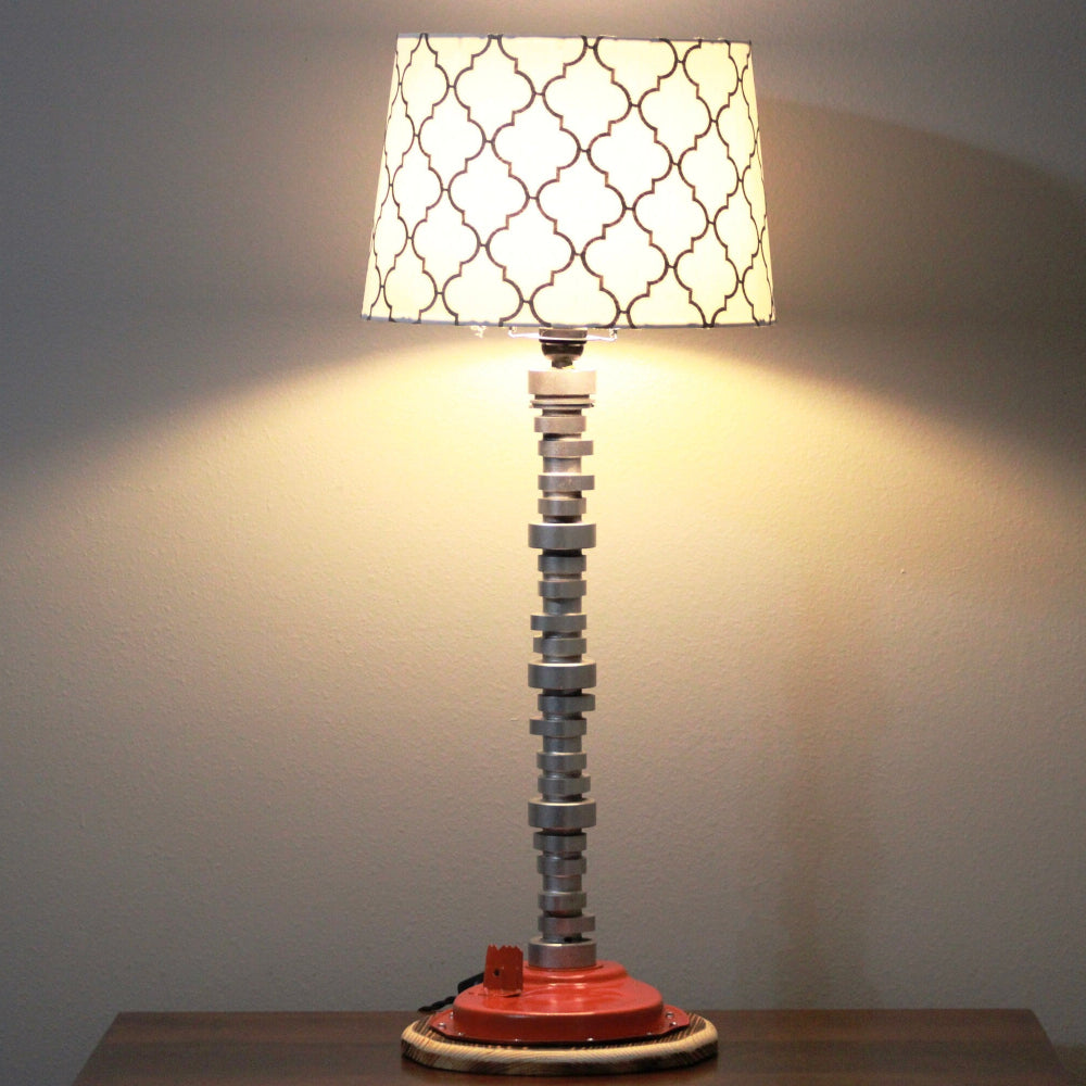 Decorative table lamp with a unique base and patterned shade on a plain background
