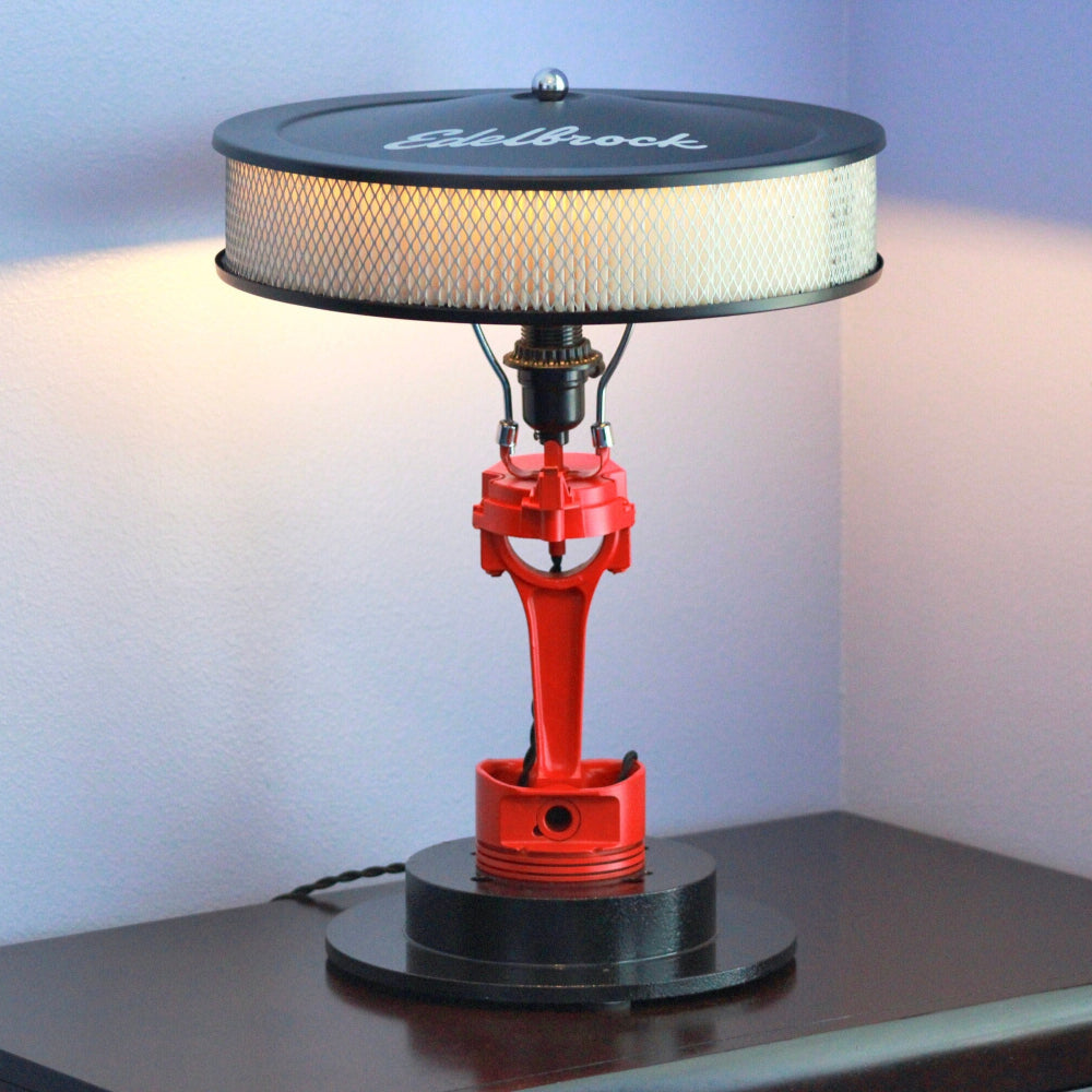 Decorative lamp with red piston design on a black base against a white background