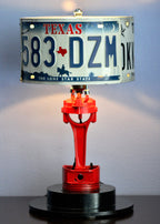 Lamp with Texas license plate shade and red metal base on a dark surface.