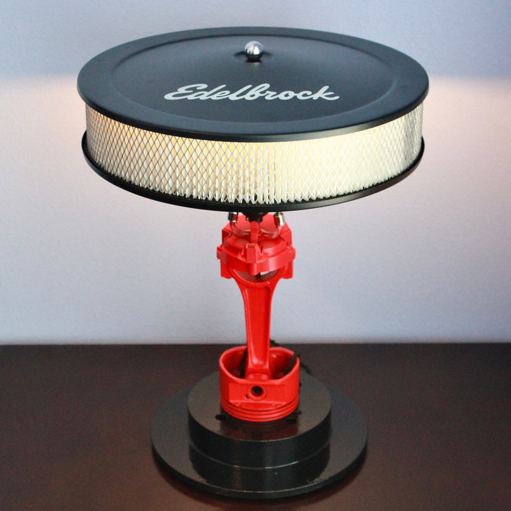 Decorative item with red valve and black air filter on a stand, featuring the Edelbrock logo.