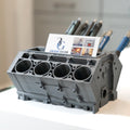 Gray engine block pen holder with business card on a blurred background