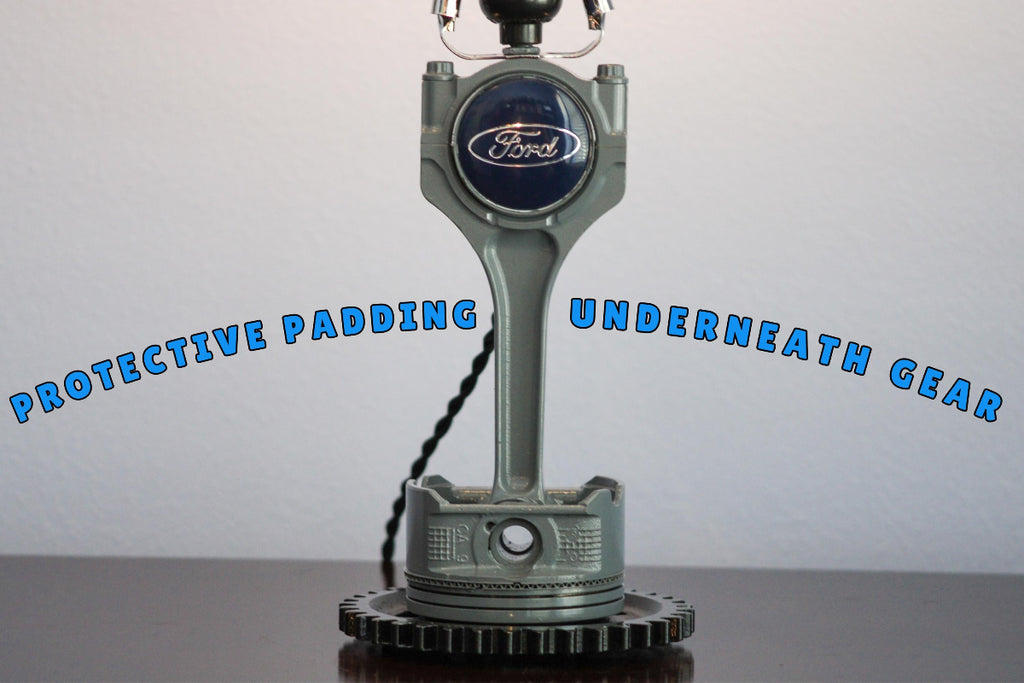 Ford engine block lamp with text 'Protective padding underneath gear' on a white background