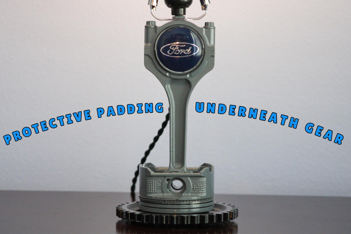 Ford engine block lamp with text 'Protective padding underneath gear' on a white background