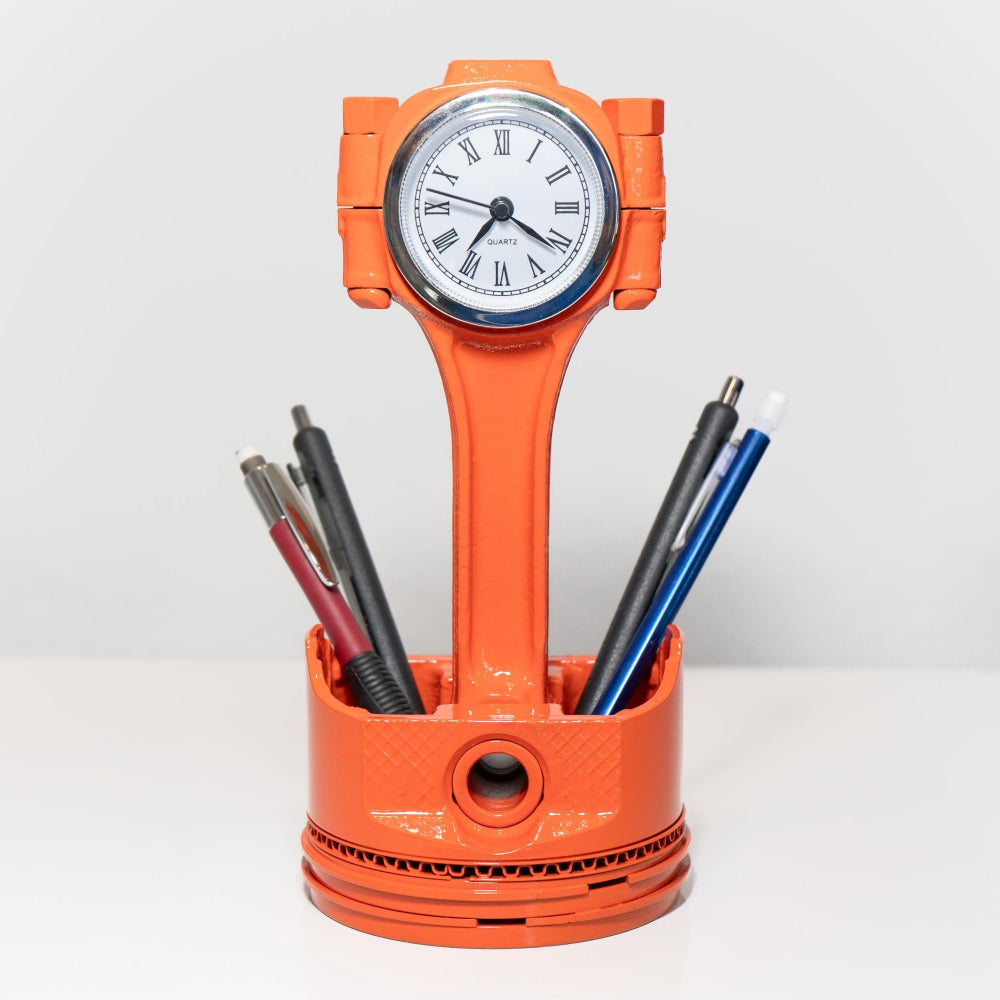 Orange clock-shaped pen holder with a clock face and pens on a white background