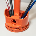 Orange pen holder with multiple pens on a white surface