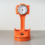 Orange clock-shaped object on a gray surface with a white background