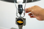 Hand adjusting a light bulb in a fixture with a Chevrolet logo on a white background