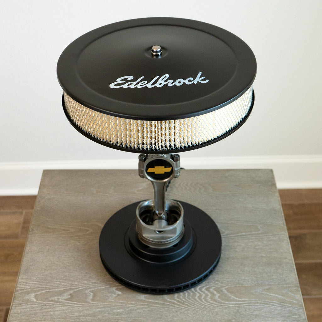 Edelbrock air filter on a wooden surface with a white background