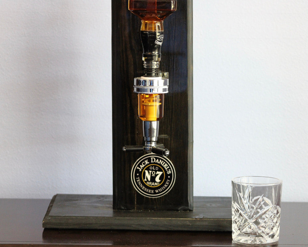 Black Daniel's whiskey decanter with a glass on a wooden surface