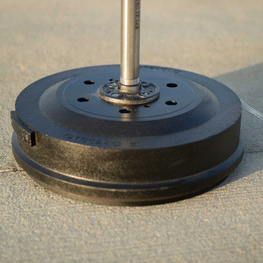 Black weight plate with a metal bar on a concrete floor