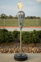 Vintage parking meter with light bulb on top in an outdoor setting
