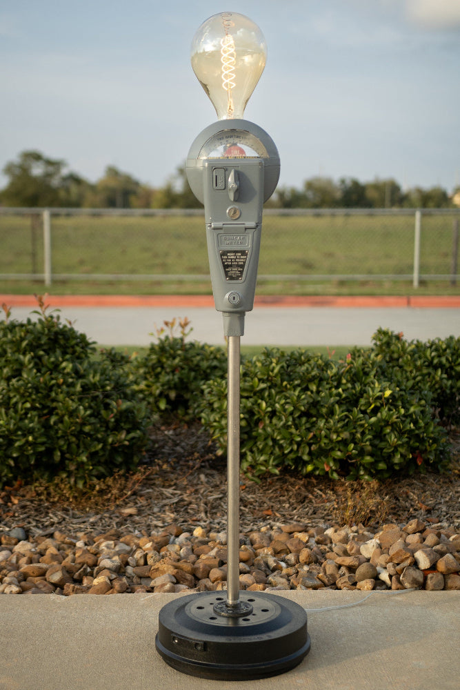 Vintage parking meter with light bulb on top in an outdoor setting