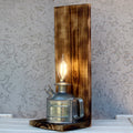 Vintage-style lamp with a wooden base and metal container on a textured wall background