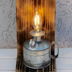 Vintage-style oil lamp with a lit bulb on a textured surface