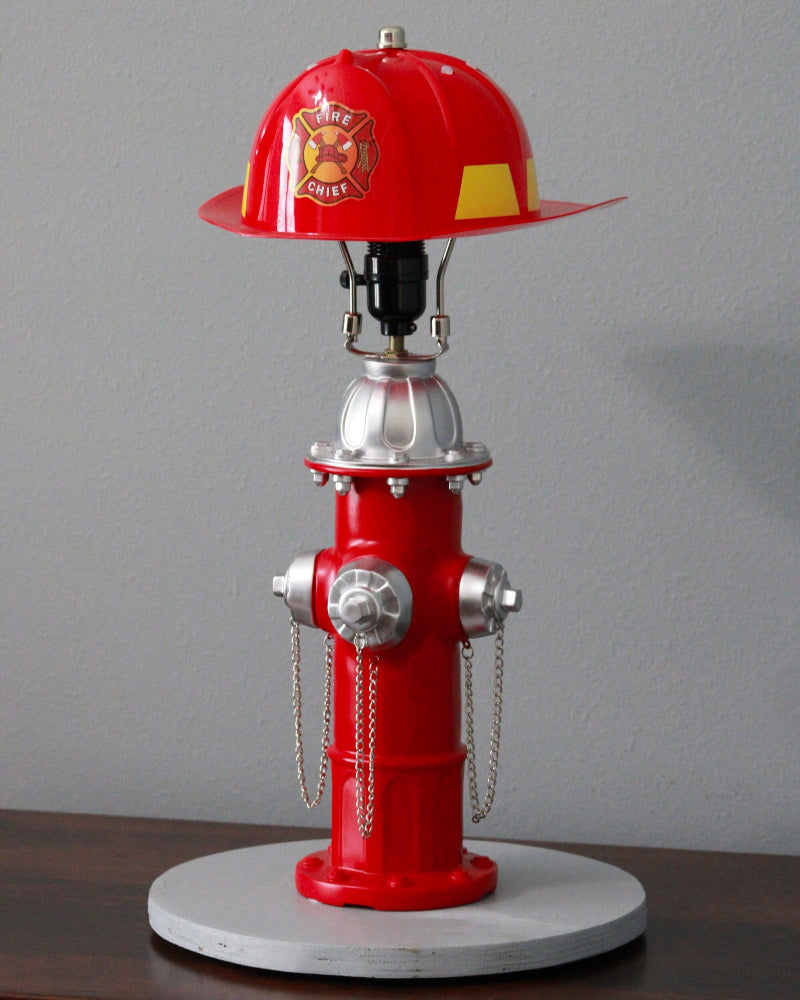 Red fire hydrant lamp with a helmet on top against a gray background