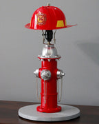 Red fire hydrant lamp with a helmet on top against a gray background