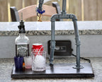 Bar setup with Jack Daniel's whiskey bottle, Coca-Cola can, and ice cubes on a stand.