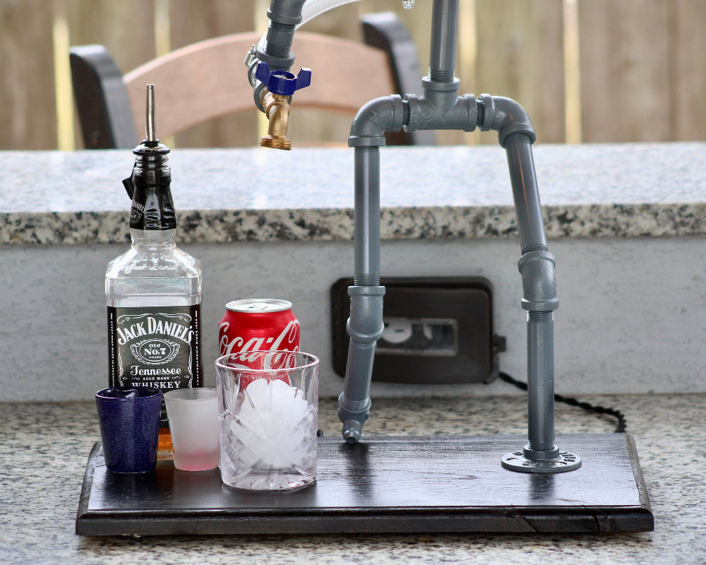 Bar setup with Jack Daniel's whiskey bottle, Coca-Cola can, and ice cubes on a stand.
