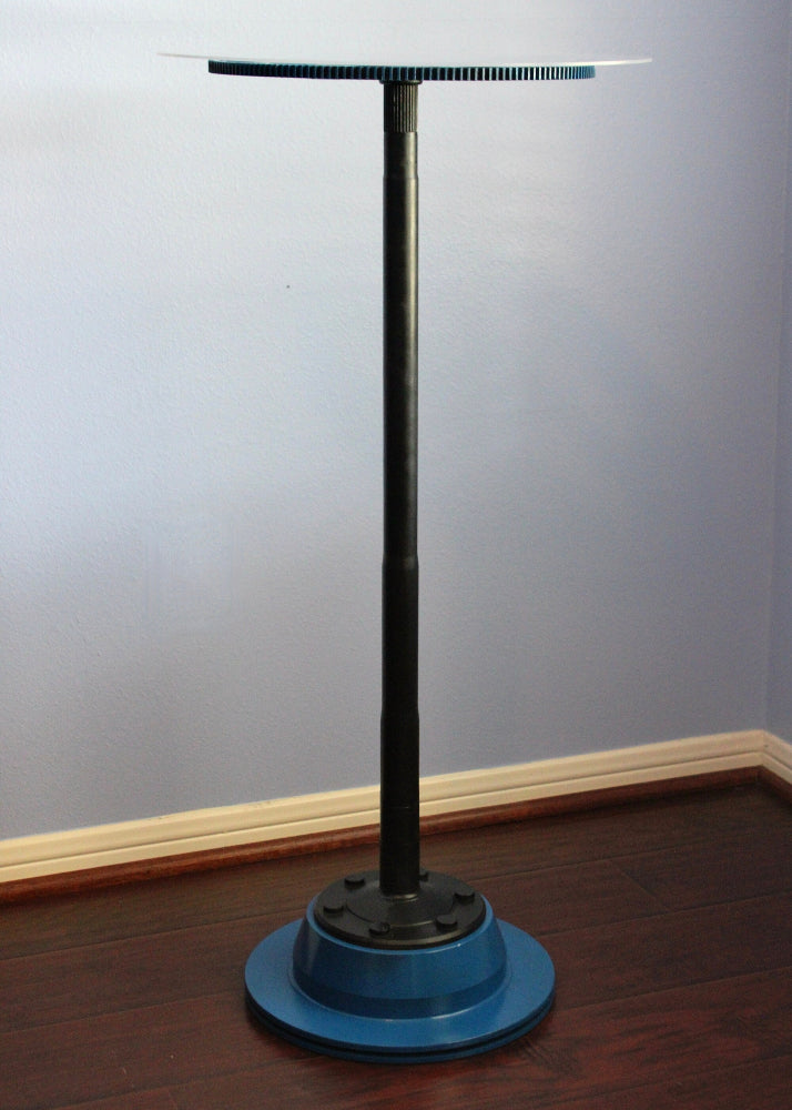 Metal stand with a round blue base against a gray wall.
