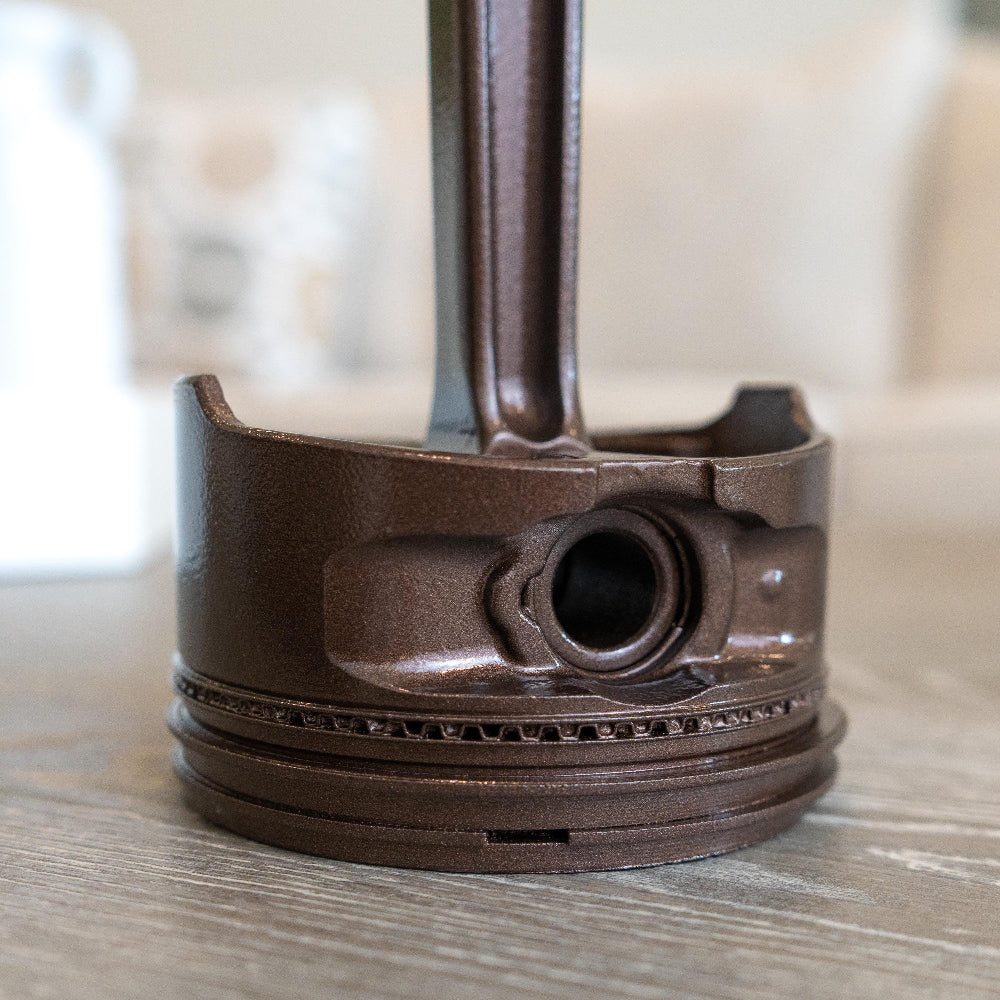 Close-up of a metallic piston on a wooden surface with a blurred background