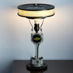 Lamp made from automotive parts on a dark surface with a light gray background