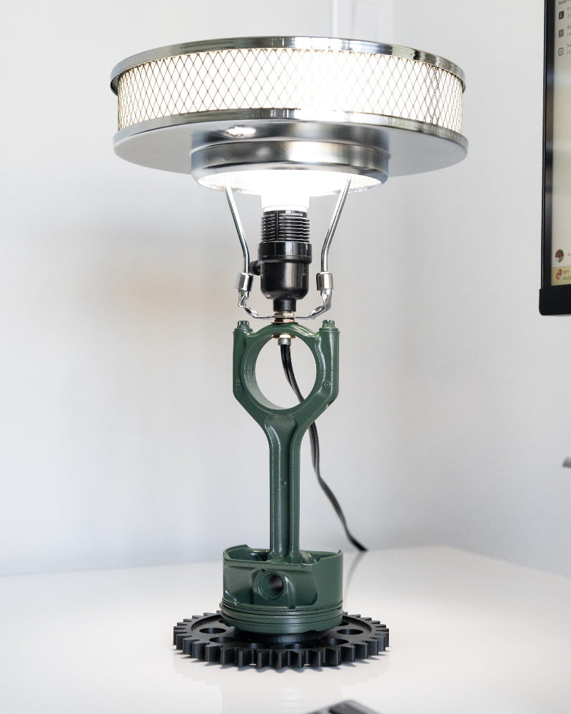 Desk lamp with green metal base and silver shade on a white surface
