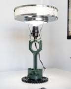 Desk lamp with green metal base and silver shade on a white surface