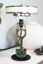 Lamp with unique design featuring a green metal component on a white surface.