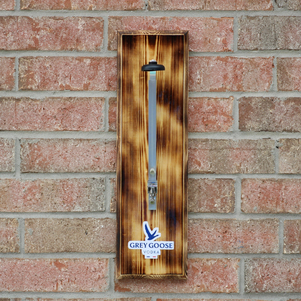 Wooden bottle opener with Grey Goose branding on a brick wall