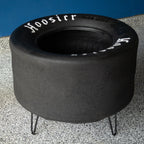 Black tire-shaped fire pit with 'Hoosier' branding on a concrete surface.