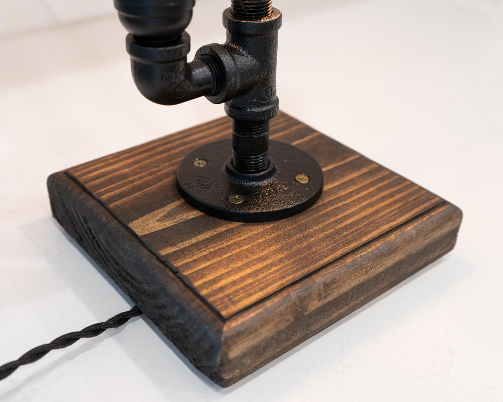 Wooden lamp base with black metal fitting on a white background