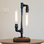 Industrial-style table lamp with black metal pipes on a wooden surface.