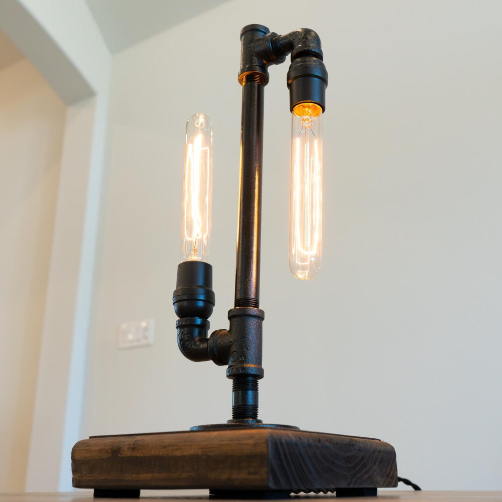 Industrial-style lamp with wooden base and metal pipes on a table.