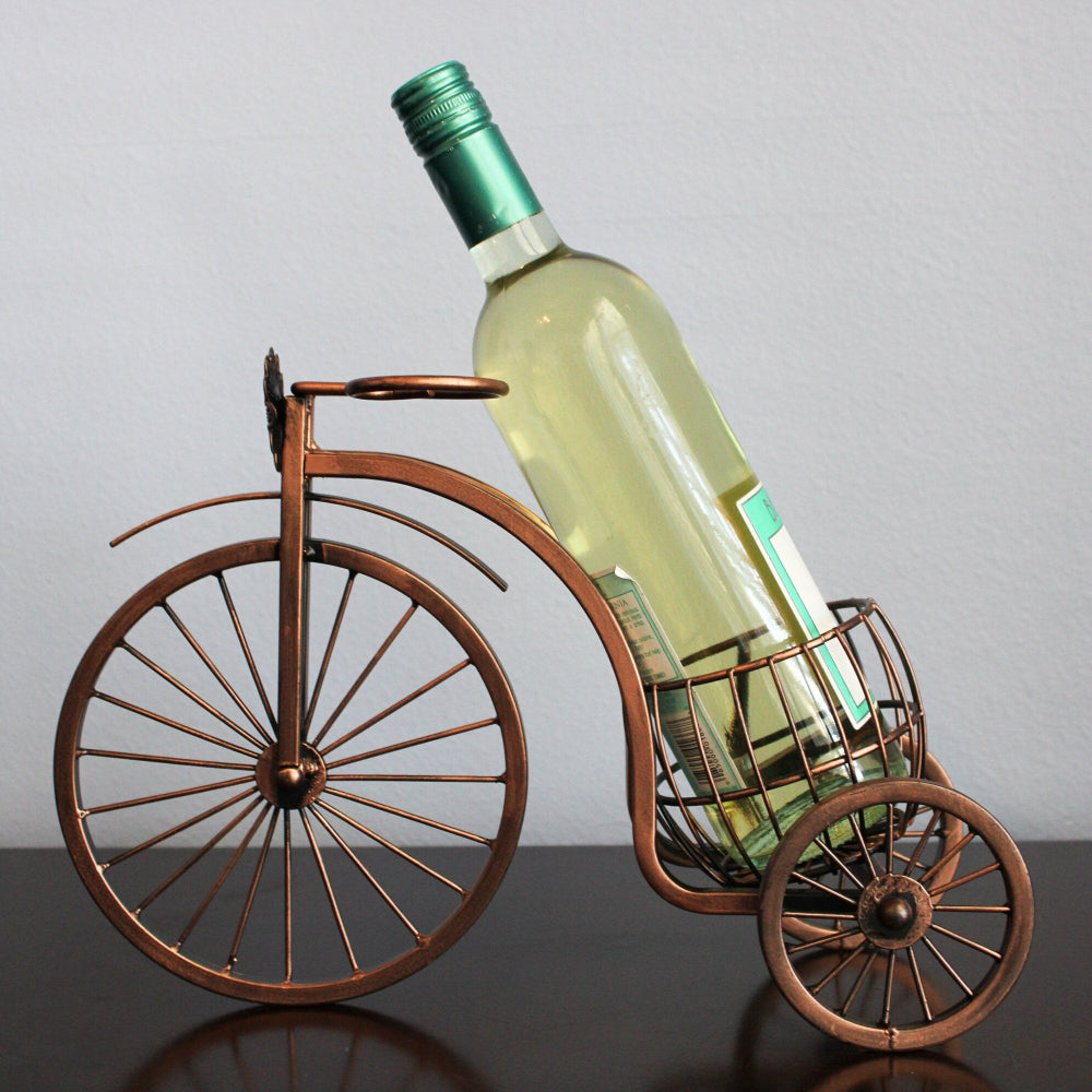 Wine bottle in a decorative bicycle holder against a plain background
