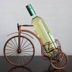 Wine bottle in a decorative bicycle holder against a plain background
