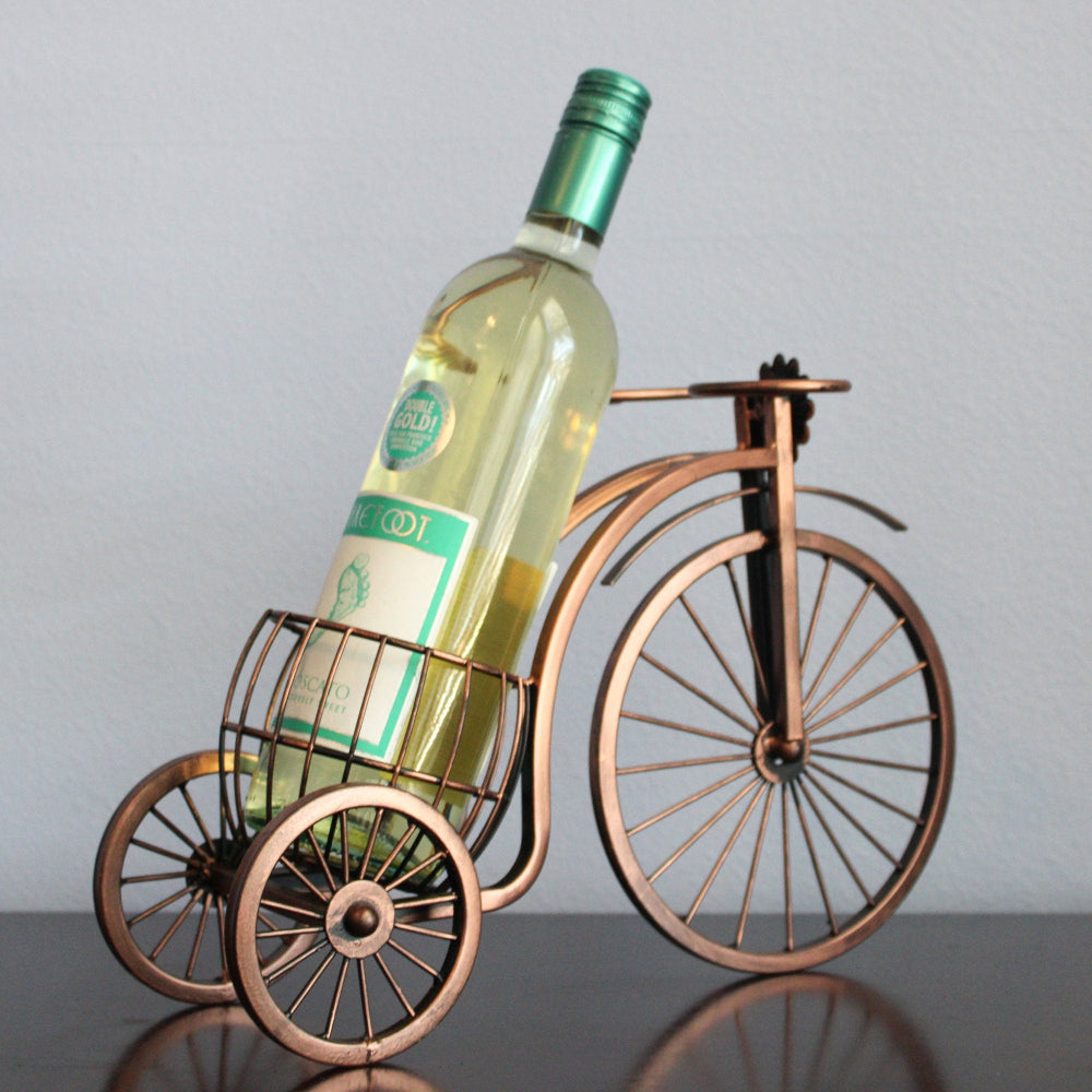 Wine bottle in a decorative bicycle holder against a plain background
