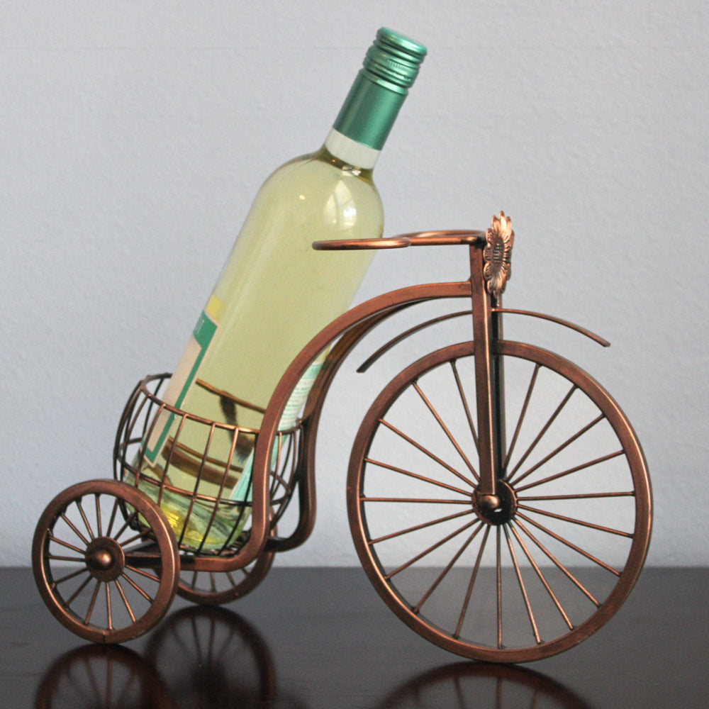 Wine bottle on a miniature bicycle decorative item against a plain background