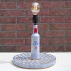 Lamp made from a Michelob Ultra beer bottle on a textured base against a brick wall.