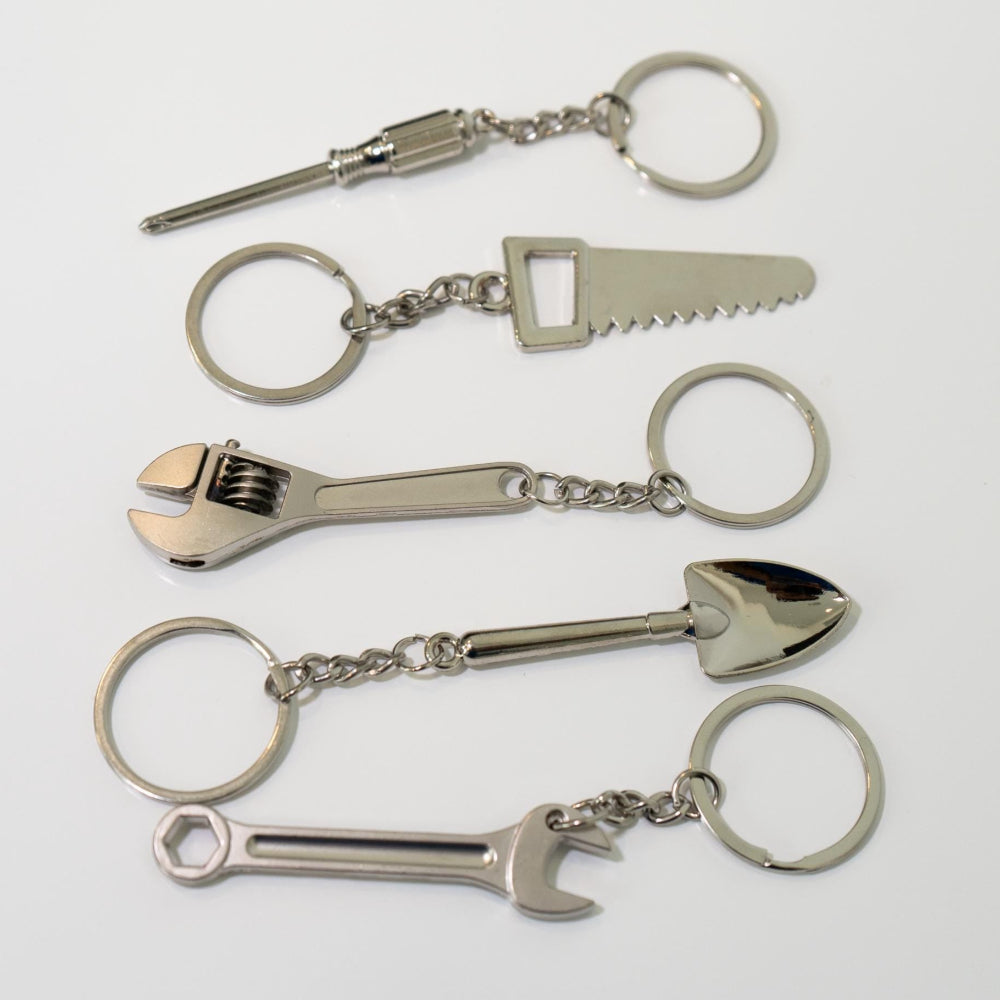 Set of metal keychains shaped like tools on a white background