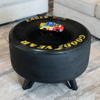 Black tire-shaped ottoman with car design on a wooden floor.