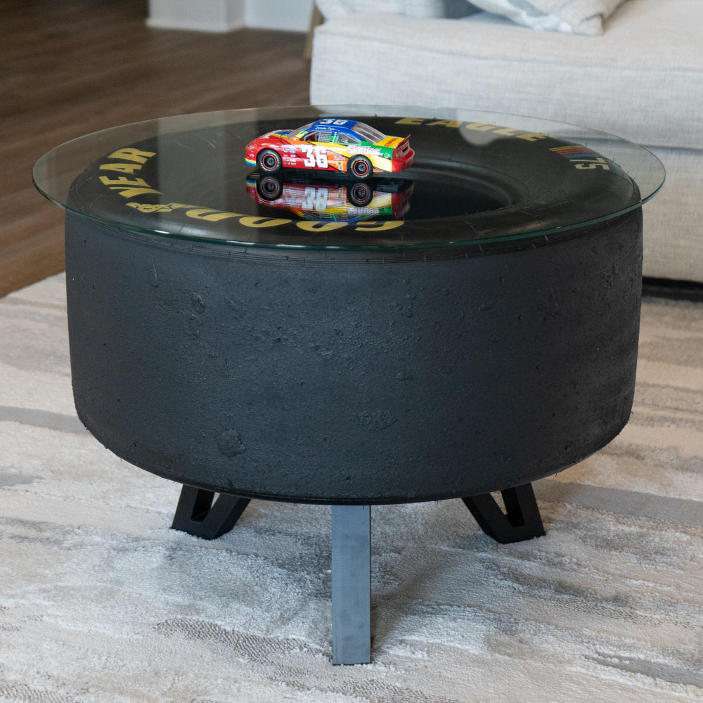 Black coffee table with a glass top displaying a colorful toy car in a living room setting.