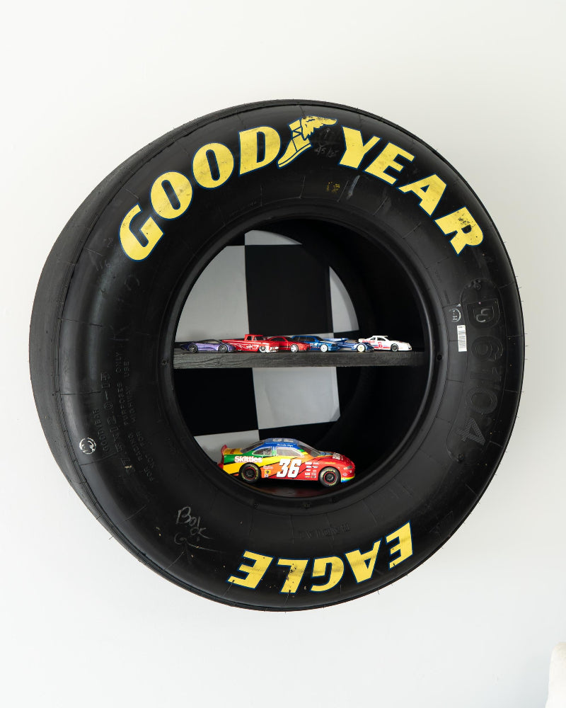 Goodyear tire with a shelf inside, displaying small model cars.