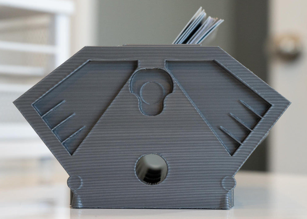 Gray geometric desk organizer with books on a blurred background
