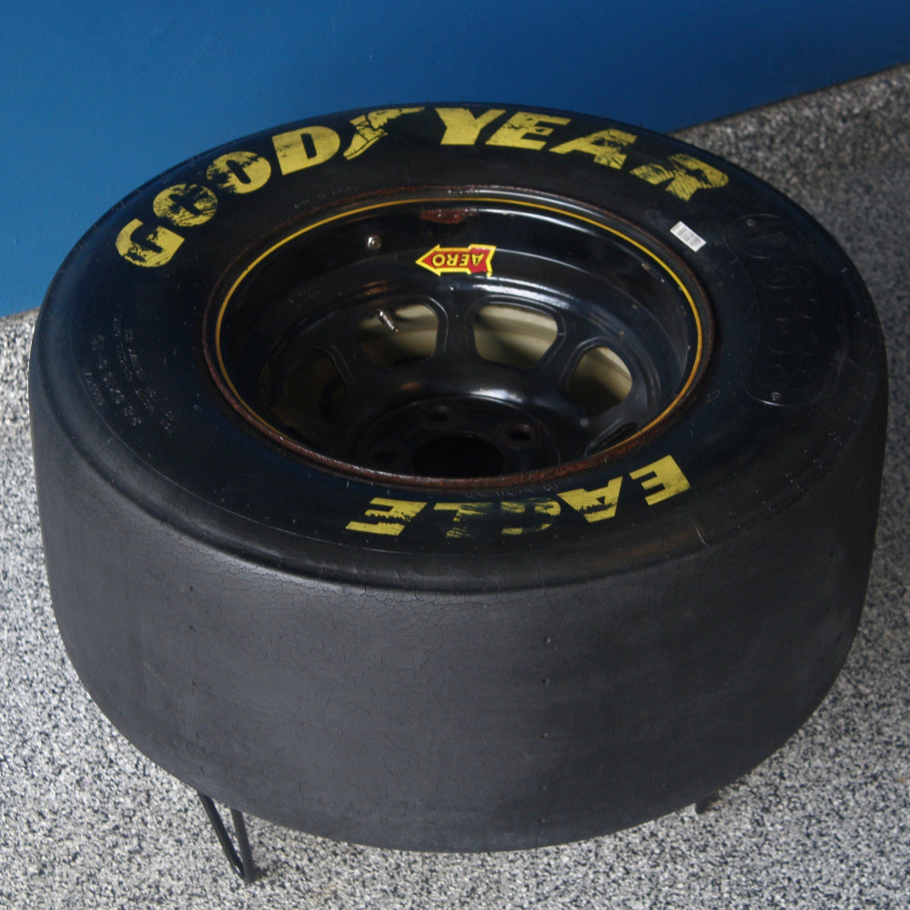 Goodyear racing tire on a gray surface with a blue background